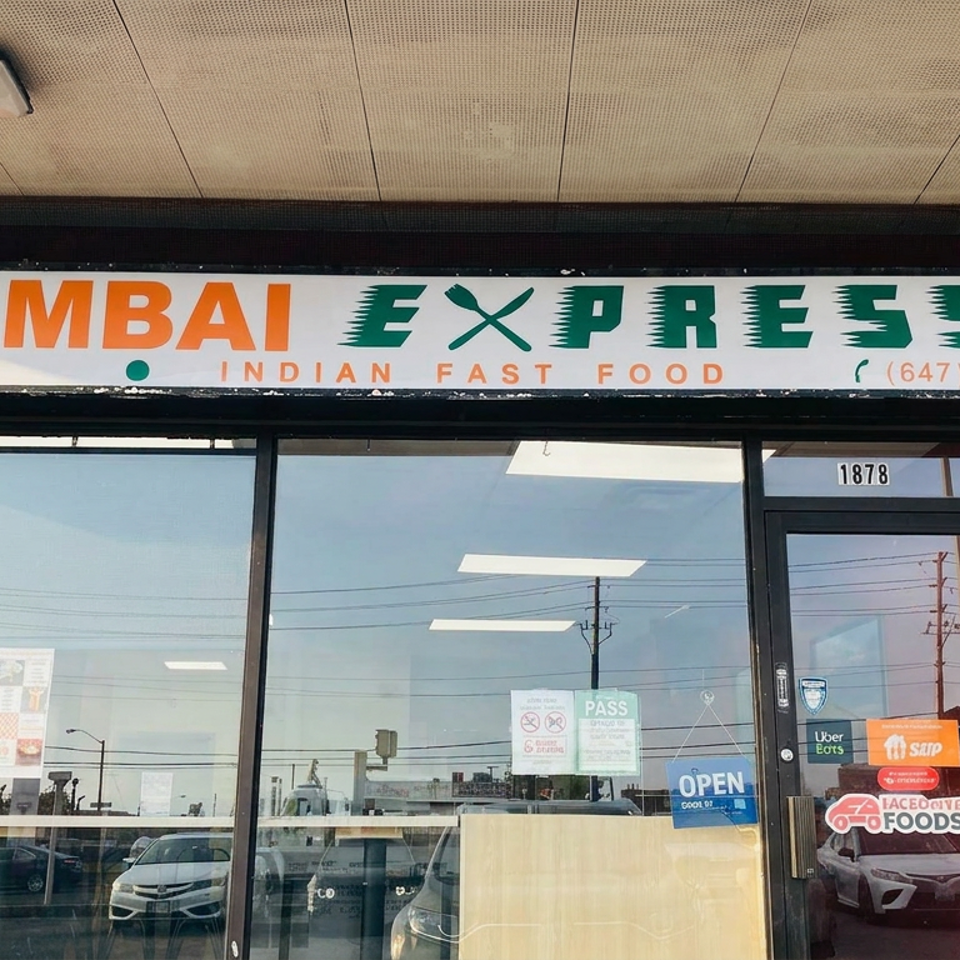 Mumbai Express storefront with signage advertising pure vegetarian Indian fast food, glass entrance, delivery decals, and address 1878.